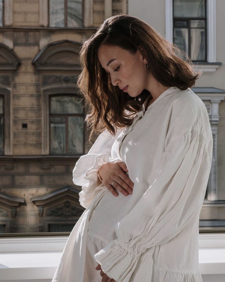 Una donna incinta vicino alla finestra